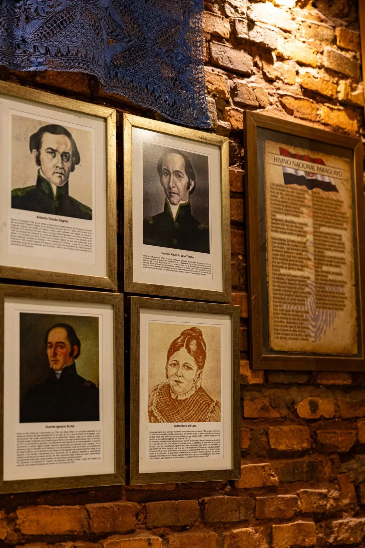 Pared con retratos de próceres paraguayos y el Himno Nacional